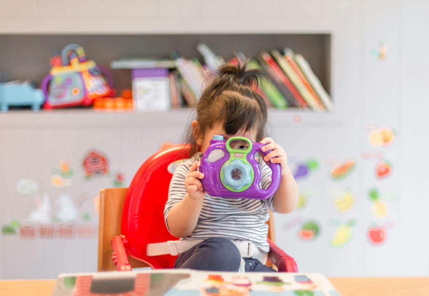 Illustrative family-life photograph of a child playing with a camera