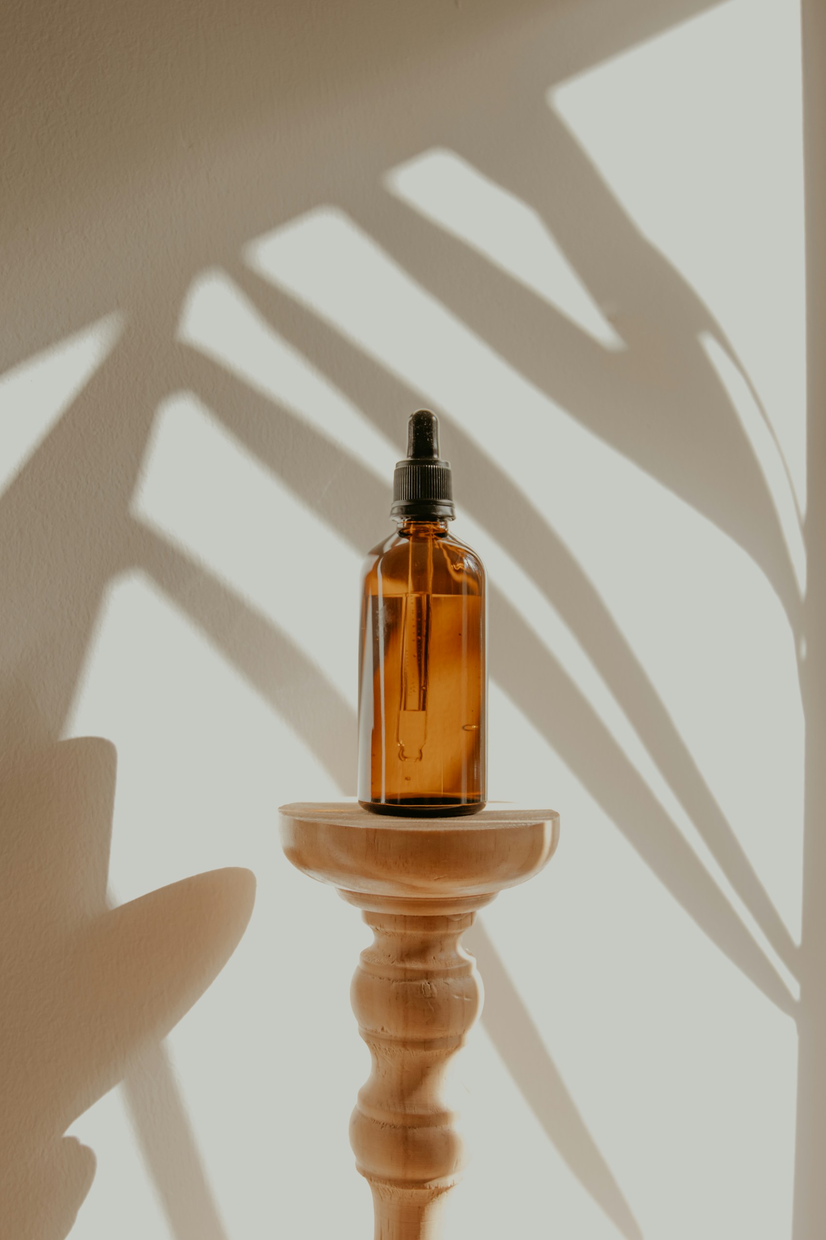Amber glass bottle, light and a botanical shadow