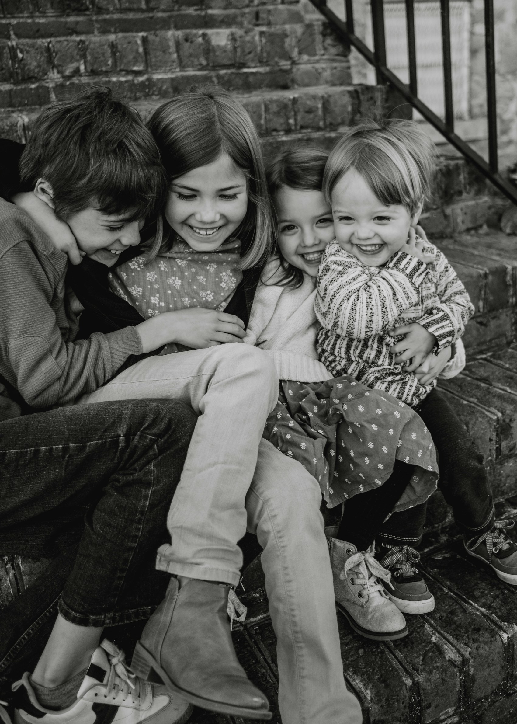 Three siblings laughing, captured in black and white